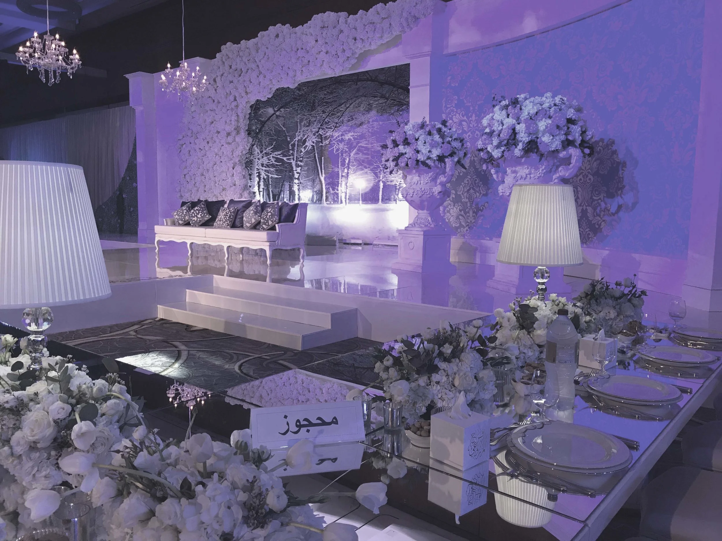 All-white wedding stage set with floral arch and chandeliers